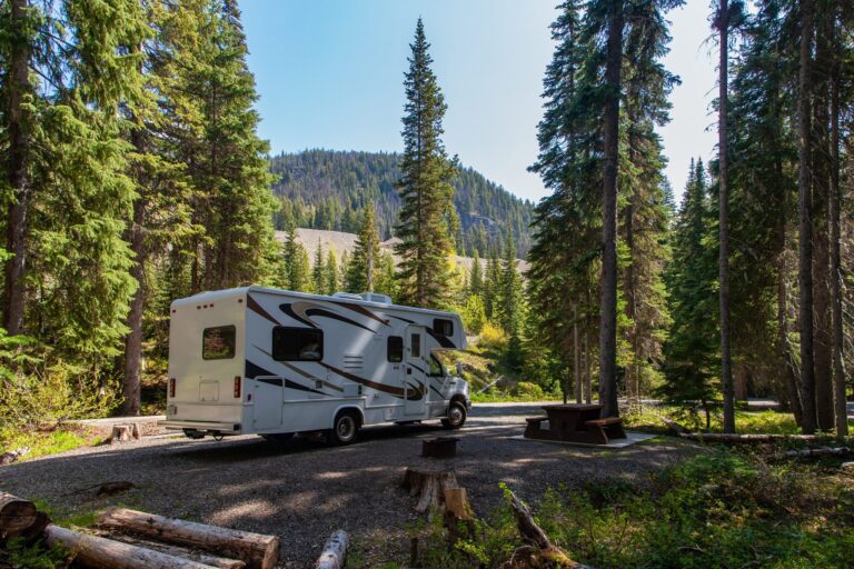 Sicher mit dem Wohnmobil unterwegs beautiful campsite mountains with rv wooden bench scaled Versicherungspapa