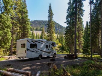 Beautiful campsite in the mountains with an RV and wooden bench. Erstes Fahrradpolicen-Rating legt große Unterschiede offen beautiful campsite mountains with rv wooden bench scaled Versicherungspapa