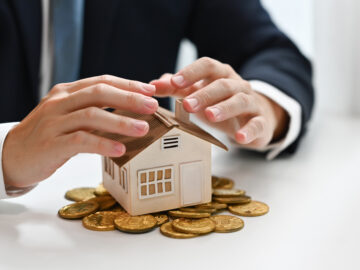 Businessman hands protecting house model and pile of gold coins. Real estate, property investment and save money concept Startseite businessman hands protecting house model and pile 2024 12 02 06 04 03 utc Versicherungspapa