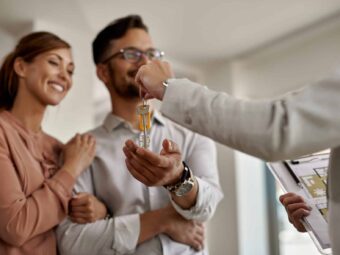 Close-up of real estate agent giving new house keys to a couple. Silberstreif am deutschen Konjunkturhorizont closeup real estate agent giving couple keys their new home scaled Versicherungspapa