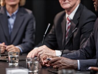 Hands of Black Man Sitting at Table while Speaking at Political Meeting Weiterer offener Immobilienfonds setzt Anteilsrücknahme aus hands of black man sitting at table while speaking 2025 03 08 20 46 05 utc scaled Versicherungspapa