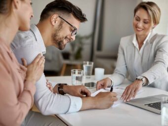 Young man signing a contract while being with his wife on a meet Silberstreif am deutschen Konjunkturhorizont happy man his wife having meeting with financial advisor signing agreement office scaled Versicherungspapa