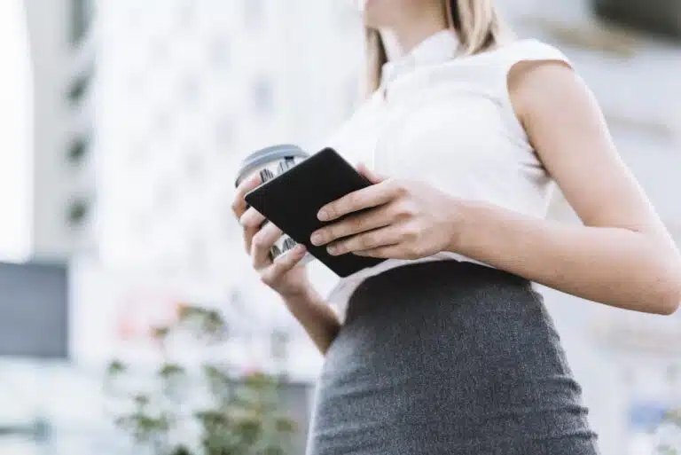 2027 kommt die digitale Brieftasche low angle view businesswoman holding smartphone disposable coffee cup outdoors scaled Versicherungspapa