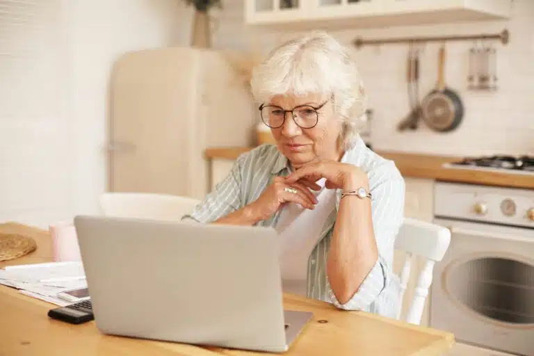 Inflation hemmt Kapitalaufbau fürs Alter modern technology old people retirement gray haired female pensioner glasses filling loan application form online sitting front laptop reading information with serious focused look scaled Versicherungspapa