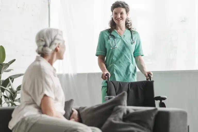 Eigenbeteiligung für stationäre Pflege steigt auf 3.245 Euro senior woman looking smiling female nurse with wheelchair scaled Versicherungspapa